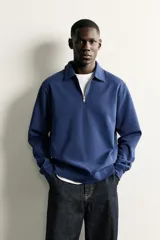 Sudadera polo de corte regular, confeccionada en tejido técnico interlock de algodón con elasticidad. Presenta cuello solapa, cierre frontal de cremallera y manga larga con puños acabados en rib.