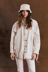 Campera oversize de jean color crudo, con cuello clásico, cierre frontal de botones metálicos, bolsillos con solapa y detalles de roturas con terminaciones deshilachadas.