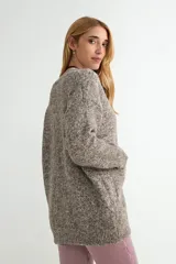 Cardigan de tejido de punto con textura jaspeada en tonos pasteles, escote en V, cierre frontal con botones oscuros y bolsillos delanteros.