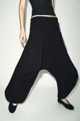 Pantalón de tiro bajo con diseño holgado y fluido, confeccionado en viscosa. Presenta una cintura ancha con detalle drapeado y puños elásticos en los tobillos.