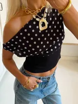 Top asimétrico negro con lunares blancos, con un hombro descubierto y detalle de elástico en la cintura.