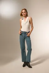 Pantalon de corte recto y tiro medio, confeccionado en denim color gris oscuro. Presenta bolsillos delanteros decorados con tachas metálicas pequeñas en los bordes y cierre frontal con botón y cremallera.