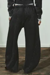 Pantalón de tiro medio con cintura elástica, confeccionado en mezcla de algodón con efecto lavado oscuro. Presenta un corte ancho y voluminoso, con paneles curvos cosidos en los laterales de las piernas.