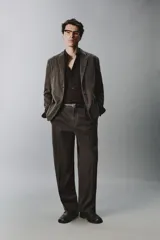 Pantalón relaxed fit de traje color marrón oscuro, confeccionado en tejido con mezcla de algodón. Cuenta con bolsillos frontales, bolsillos traseros de doble vivo con botón y efecto lavado. Cierre frontal con cremallera y botón.