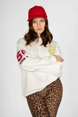 Sweater blanco de algodón con cuello redondo y mangas largas. Estampado frontal con las letras "NYC" en amarillo y rojo, y número "51" en la manga.