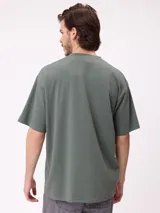 Remera negra de corte holgado con pequeño logo bordado en el pecho que incluye un diseño de pez y la marca Rusty.