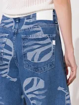 Pantalón de jean azul con estampado de siluetas de animales en color gris, de corte slouchy, tiro alto y piernas anchas que se angostan hacia el tobillo.
