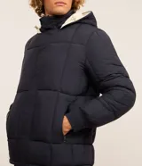 Campera puffer de hombre reversible, con diseño acolchado, cuello alto, capucha y cierre frontal.