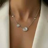 Gargantilla de plata 925 con diseño de cadena fina que incorpora tres dijes circulares: uno central con nácar, uno lateral con pavé de circonias y dos dijes laterales lisos de plata.