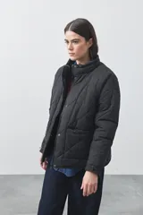 Campera acolchada de nylon color negro, con cuello alto, cierre frontal y botones a presión. Presenta un diseño de rombos y forro interior suave.