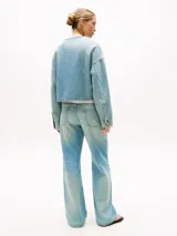 Campera de denim rígido en mezcla de algodón y lyocell, color celeste lavado. Presenta un corte cropped y oversize, sin cuello, con cierre frontal de tres botones dorados cepillados y hombros caídos.