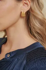 Caravana de diseño tipo argolla con textura acanalada en acabado dorado brillante.