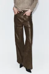 Pantalón de tiro medio confeccionado en tejido efecto piel, con diseño de cinco bolsillos y cierre frontal con cremallera y botón.