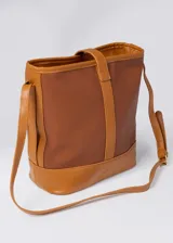 Bolso tipo tote de cuero sintético color marrón, con doble asa corta para llevar al hombro. Tiene un compartimento principal con cierre y un bolsillo interno.