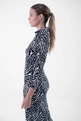 Vestido midi de corte ajustado, con estampado animal print tipo cebra en blanco y negro, cuello camisero, escote en V y cierre frontal con botones dorados.