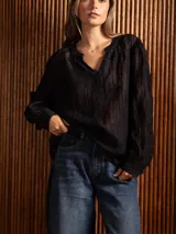 Blusa de tela liviana color bordó, con escote en V y detalles de bordado floral tono sobre tono. Presenta mangas largas con leve volumen y puños abotonados.