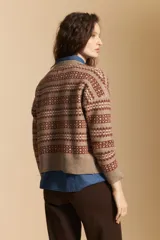 Cardigan corto de tejido jacquard con diseño geométrico en tonos beige y crema, con cierre frontal de botones y cuello redondo.