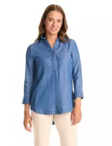 Blusa de lyocell color azul con efecto denim, cuello camisero con solapa y escote en V con cierre de un botón. Presenta mangas tres cuartos con terminación doblada y ruedo redondeado.