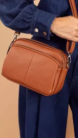 Bandolera de símil cuero color rojo, con doble bolsillo principal, un bolsillo frontal y un bolsillo trasero. Incluye correa ajustable.