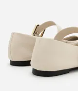 Zapatilla chatita de cuero color crema, con punta redonda, plantilla cómoda y tira con hebilla dorada en la parte superior.