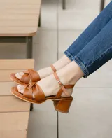 Sandalias de cuero color dorado, con plataforma y taco cuadrado. Presentan tiras cruzadas en el empeine y pulsera al tobillo con hebilla.