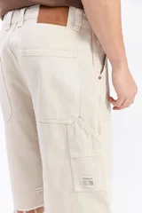 Bermuda carpenter de jean con corte amplio, bolsillos grandes y detalles inspirados en la ropa de trabajo. Presenta un lavado desgastado y ruedo desflecado.