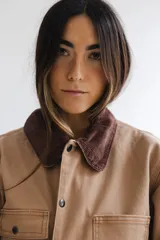 Campera estilo cargo color tostado con cuello de pana marrón, múltiples bolsillos delanteros y cierre frontal con botones a presión.