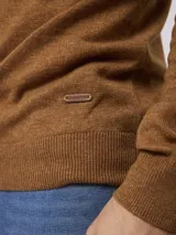 Sweater de tejido de punto en color azul, con cuello alto y cierre frontal parcial. Presenta mangas largas con puños acanalados y un pequeño detalle bordado en el pecho.