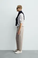 Pantalón jogger color beige de tejido transpirable y elástico con cintura elástica ajustable con cordón, bolsillos frontales y bajo con vuelta.