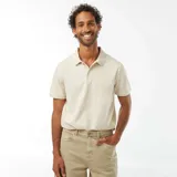 Remera tipo polo color beige claro, de piqué de algodón, con cuello clásico, tapeta de dos botones y mangas cortas.