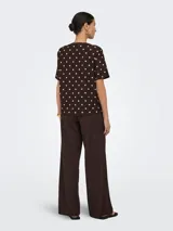 Pantalón suelto color marrón con estampado de lunares blancos, tiro medio y cintura elástica con cordón de ajuste.