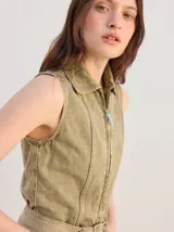 Enterito largo de denim color verde militar, sin mangas, con cuello camisero, cierre frontal completo y bolsillos laterales. Incluye cinturón ajustable del mismo material con hebilla metálica.