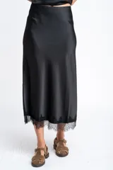 Falda midi negra de acabado satinado, corte al bies, con detalle de encaje en el ruedo.
