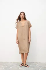 Vestido color beige de lino, corte recto, con cuello en V y mangas cortas. Tiene bolsillos laterales.