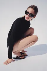 Chaqueta de punto negra con cuello subido y cierre frontal con cremallera, de manga larga y diseño ajustado.