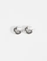 Aros tipo argolla gruesos de diseño compacto y acabado brillante en tono plateado.