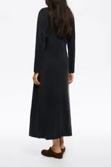 Vestido de largo midi en color negro con corte en línea A y vuelo. Posee escote barco, mangas largas tipo murciélago ajustadas en los puños y detalles de pespuntes decorativos a contraste. Está confeccionado en una mezcla de cupro y elastano.
