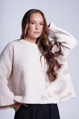 Sweater de punto color crema con estampado animal print en tonos beige. Tiene cuello redondo y mangas largas acampanadas.