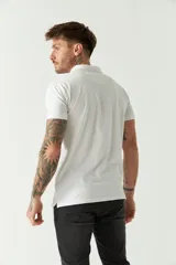 Remera polo blanca de manga corta, con cuello clásico, cierre de tres botones y logo estampado en el pecho.