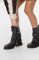 Bota corta de cuero color marrón claro (visón) con caña arrugada y suela track negra gruesa. Presenta un detalle de tira de cuero con hebilla en el tobillo.