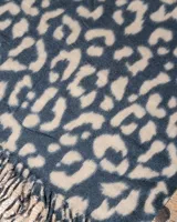 Bufanda de gran tamaño con estampado animal print en tonos negro y beige, con terminación de flecos en los extremos.