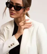 Blazer blanco de punto roma con cuello solapa, corte sastrero alargado, bolsillos y cierre con corchete.