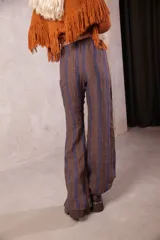 Pantalon de tiro medio con cintura elastizada, confeccionado en lino. Presenta un corte amplio tipo oxford con diseño de rayas verticales en tonos marrones y azules.