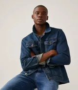 Campera trucker de jean azul oscuro, con cuello tradicional, cierre frontal con botones, cuatro bolsillos y mangas largas.