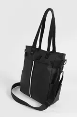 Bolso tipo tote negro confeccionado en PVC y poliéster, con compartimento principal con cierre, bolsillos laterales y bolsillo trasero con cierre. Incluye asas superiores de mano, correa ajustable removible y un estuche removible para paleta de pádel con detalle de franja vertical blanca.