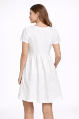 Vestido corto negro de broderie, con mangas cortas abullonadas y escote en V. Presenta un corte imperio con frunce en la cintura y falda acampanada.