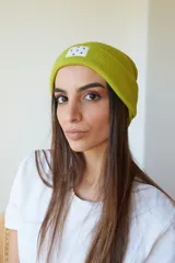 Gorro de lana color lila con etiqueta cuadrada blanca con diseño de triángulos negros.
