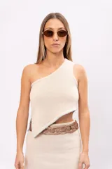 Top tejido en algodón color crudo, con diseño asimétrico de un hombro y detalle de pespuntes celestes en los bordes.