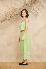 Conjunto de dos piezas compuesto por un crop top de breteles anchos y una pollera midi, ambos en color azul con detalles de bordado floral blanco en el ruedo y el lateral del top.