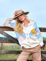 Cardigan de punto con diseño de rombos en tonos crudo, celeste y mostaza. Presenta cuello en V, cierre frontal con botones y puños acanalados.